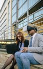 Jovem empresário e mulher usando óculos VR em frente ao prédio de escritórios — Fotografia de Stock