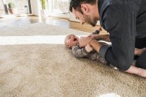 Padre e hijo jugando en la alfombra en casa - foto de stock