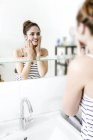 Junge attraktive kaukasische Frau wäscht Gesicht und schaut in den Spiegel — Stockfoto