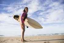 Молодий сміється жінка з дошки для серфінгу на піщаний пляж — стокове фото