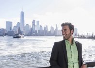 Sonriente hombre de pie en el paseo marítimo de Nueva Jersey con vista a Manhattan, EE.UU. — Stock Photo