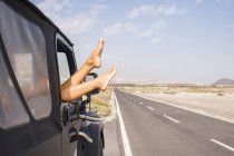 Spain, Tenerife, legs of woman leaning out of car window — Stock Photo