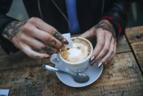 Primo piano di mani femminili che versano lo zucchero in un caffè — Foto stock
