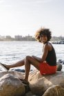 Retrato de uma jovem mulher sentada na margem do rio rochoso — Fotografia de Stock