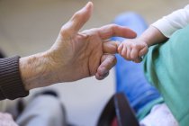 Крупный план малыша, держащего палец прабабушки — стоковое фото