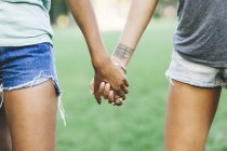 Close Up Of Two Women Holding Hands In A Park Front View Casual Clothing Stock Photo