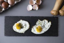 Vue de dessus des œufs frits sur ardoise noire — Photo de stock