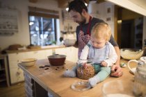 Padre y bebé haciendo un pastel en la cocina - foto de stock