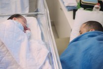 Père dormant à côté d'un nouveau-né à l'hôpital — Photo de stock