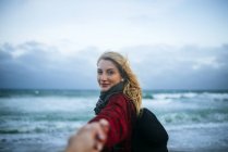 Jovem mulher tomando a mão de um homem na praia
. — Fotografia de Stock