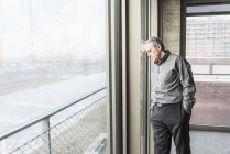 Empresário encostado à janela — Fotografia de Stock