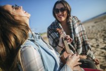 Two women sitting on the beach with ukulele in Spain, Andalusia, Vejer de la Frontera — Stock Photo