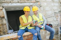 Two construction workers looking at a mobile phone at break time. — Stock Photo