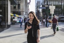 Retrato de mujer asiática joven usando teléfono inteligente en la calle - foto de stock