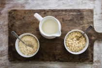 Top view of oat flakes in bowls with milk — Stock Photo