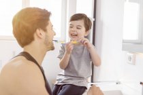 Happy father and son brushing teeth together in bathroom — Stock Photo