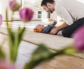 Vater spielt mit Baby-Sohn auf Teppich mit Kopfhörern — Stockfoto