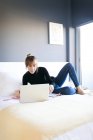 Woman lying on bed and using laptop — Stock Photo