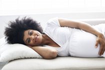 Portrait of pregnant woman relaxing on couch — Stock Photo