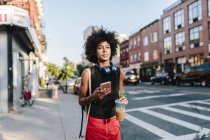 Portrait of young woman walking at street with smartphone — Stock Photo