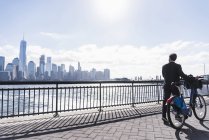 Man walking with bicycle at New Jersey waterfront with view to Manhattan, USA — Stock Photo