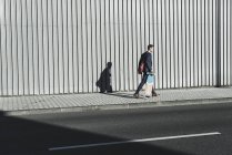Молодий бізнесмен, що йде зі скейтбордом на тротуарі — стокове фото