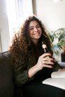 Portrait of young smiling woman holding bottle of beer and book — Stock Photo