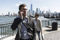 EE.UU., hombre de negocios en el teléfono celular en el paseo marítimo de Nueva Jersey con vistas a Manhattan — Stock Photo