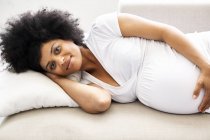 Retrato de mulher grávida relaxando no sofá — Fotografia de Stock