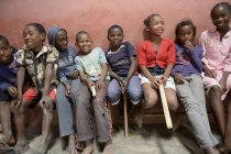 Madagaskar, Fianarantsoa, Schulkinder sitzen auf einer Bank in einer Reihe — Stockfoto