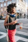 Portrait of young woman walking with smartphone and drink — Stock Photo
