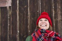 Portrait de femme souriante portant un chapeau rouge en hiver levant les yeux — Photo de stock