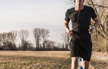 Cropped portrait of young man running in field — Stock Photo