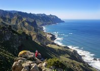 Spanien, Kanarische Inseln, Teneriffa, Anaga-Berge, Frauen sitzen an der Küste und betrachten das Dorf Almaciga — Stockfoto