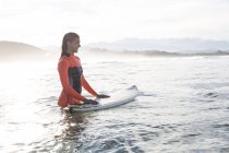 Jovem mulher na prancha de surf no oceano esperando por onda — Fotografia de Stock