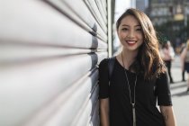 Retrato de mujer asiática joven de pie cerca de la pared - foto de stock