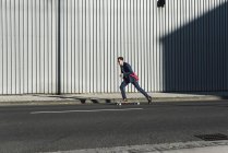 Jeune homme d'affaires à cheval skateboard dans la rue — Photo de stock
