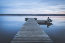 Germany, Saxony-Anhalt, woman sitting on jetty at Lake Bergwitz — Stock Photo