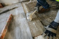 Closeup of hands of worker placing flooring with a sledgehammer. — Stock Photo