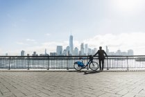 Man standing with bicycle at New Jersey waterfront with view to Manhattan, USA — Stock Photo