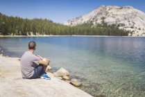 États-Unis, Californie, Parc national de Yosemite, homme assis au lac de montagne — Photo de stock