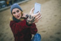 Close-up of tattooed female hand take a selfie on beach — Stock Photo