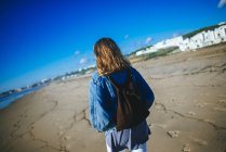 Испания, Conil de la Frontera, вид сзади на молодую женщину, прогуливающуюся по пляжу — стоковое фото