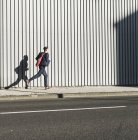 Молодий бізнесмен біжить на тротуарі вздовж будівлі — стокове фото