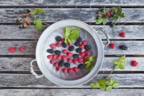 Wild raspberries and blackberries in metal tray — Stock Photo