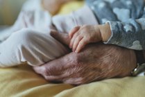 Close-up of great-granddaughter holding hand of great-grandmother — Stock Photo