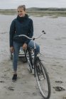Paesi Bassi, Schiermonnikoog, donna con bicicletta e rimorchio sulla spiaggia — Foto stock