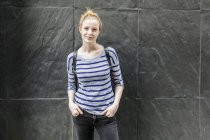 Ritratto di giovane donna in piedi vicino al muro scisto — Foto stock