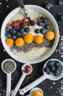 Ciotola di porridge con latte, mirtilli, chia, physalis e bacche di goji — Foto stock