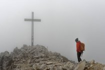 Italy, Alto Adige, man at summit cross of Weisshorn in heavy fog — Stock Photo